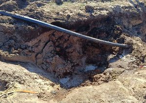Wykop ziemny. W tle widoczna część skorodowanej bomby lotniczej