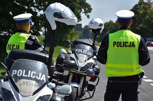 Policjanci jarosławskiej drogówki w czasie służby na drodze. Obok funkcjonariuszy znajduje się policyjny motocykl.