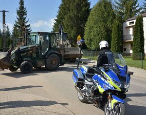 Policyjny motocykl. Przed nim policjant kieruje ruchem.