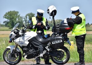 Policyjny motocykl. Przy motocyklu znajdują się policjanci.
