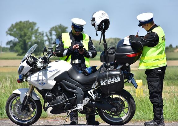 Policyjny motocykl. Przy motocyklu znajdują się policjanci.