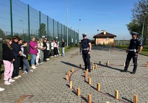 Policjant i dzieci na torze przeszkód w czasie konkursu rowerowego