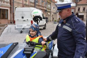 Chłopczyk na policyjnym motocyklu. Obok niego stoi policjant