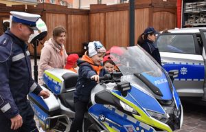 Chłopczyk na policyjnym motocyklu. Obok niego policjant