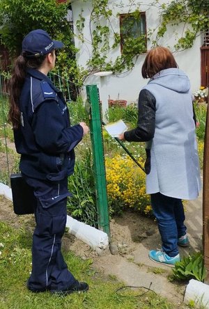 Policjantka daje ulotkę kobiecie która przebywa na działce