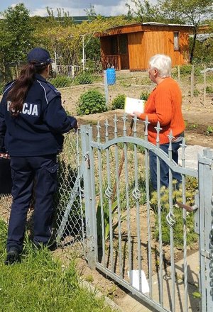 Policjantka obok niej kobieta z ulotką w ręce.