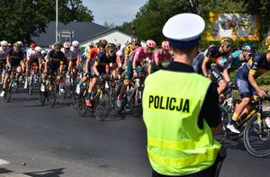 Policjant zabezpieczający trasę wyścigu. W tle kolarze