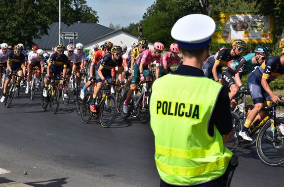 Policjant zabezpieczający trasę wyścigu. W tle kolarze