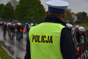 Policjant. W tle przejeżdżający kolarze