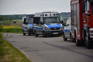 Radiowozy na poboczu drogi. Przed nimi wóz strażacki