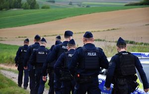 Policjanci idą polną drogą
