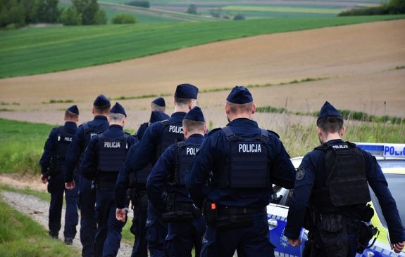 Policjanci idą polną drogą