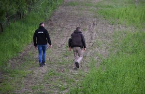 Policjanci nieumundurowani idą łąką