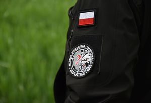 Element umundurowania policjanta. Na rękawie widoczna jest naszywka- flaga biło-czerwona oraz logo Komendy Wojewódzkiej w Rzeszowie