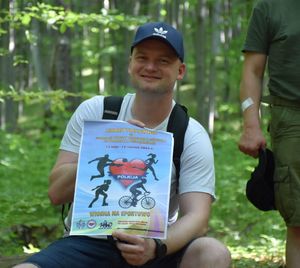 Mężczyzna trzyma w rękach plakat promujący akcję Wiosna na sportowo