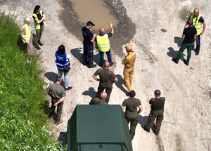 Zdjęcie z drona. Na drodze znajdują się funkcjonariusze służb mundurowych oraz osoby cywilne