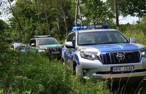 Radiowóz oraz samochód Straży Granicznej na leśnej drodze