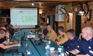 Sala na której znajdują się policjanci, strażacy oraz inne służby. Na ekranie wyświetlona jest prezentacja