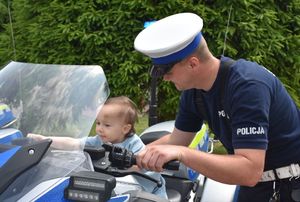 Mały chłopiec na motocyklu. Obok niego policjant