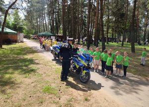 Teren leśny. Policjant z dziećmi na pikniku