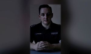 Czarno-białe zdjęcie policjanta siedzącego przy biurku