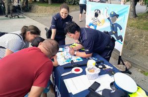 Policjantka z odwiedzającymi policyjne stoisko w czasie pikniku