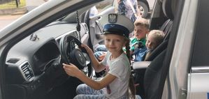 Dziewczynka w policyjnej czapce w radiwozie