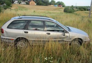 Samochód osobowy na łące. Pojazd ma uszkodzoną prawą przednią szybę oraz karoserię