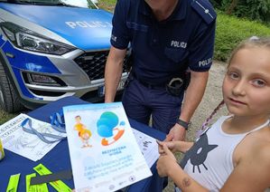 Policjant wręcza dziewczynce ulotkę