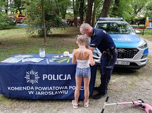 Policjant z dziewczynką przy stoisku profilaktycznym