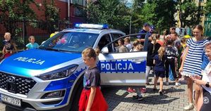 Policyjny radiowóz wokół którego znajdują się dzieci