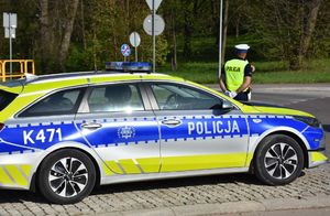 Radiowóz na drodze. Przed nim stoją policjanci