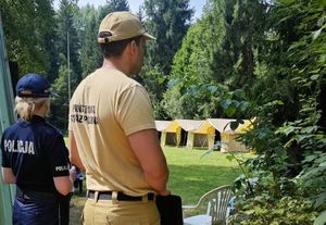 Policjantka i strażak na tle obozu harcerskiego