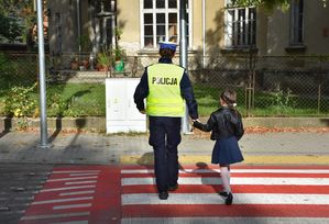 Policjant przeprowadza dziecko przez przejście dla pieszych