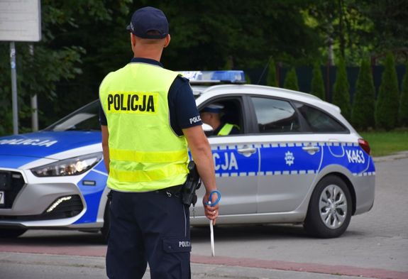 Policjant na drodze. W tle radiowóz