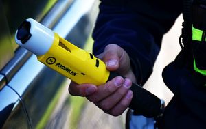 Policjant trzyma w ręce urządzenie do badania stanu trzeźwości