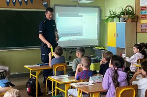 Policjant rozdaje odblaski dzieciom.