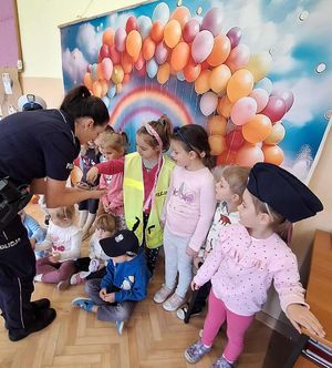 Dzieci w policyjnych czapkach. Obok nich policjantka