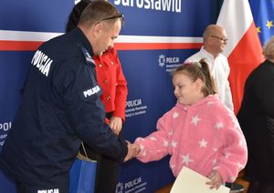 Policjant wręcza nagrodę dziewczynce