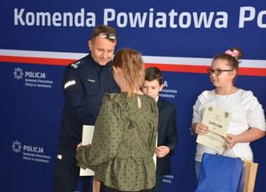 Policjant wręcza nagrodę dziecku