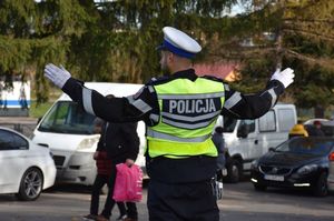 Policjant kieruje ruchem na drodze w okolicy cmentarza