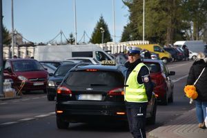 Policjant kieruje ruchem na drodze w okolicy cmentarza