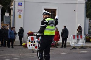 Policjant kieruje ruchem na drodze w okolicy cmentarza