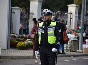 Policjant kieruje ruchem na drodze w okolicy cmentarza
