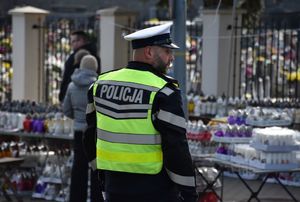 Policjant kieruje ruchem na drodze w okolicy cmentarza