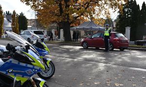 Policjant kieruje ruchem na drodze w okolicy cmentarza