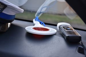 Policyjna czapka, tarcza do zatrzymywania pojazdów oraz urządzenie do badania stanu trzeźwości kierujących na podszybiu radiowozu