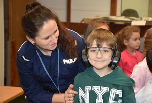 Policjantka z dzieckiem. dziecko ma założone słuchawki i okulary