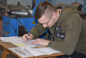 Mężczyzna wypełnia dokumenty przy stoliku