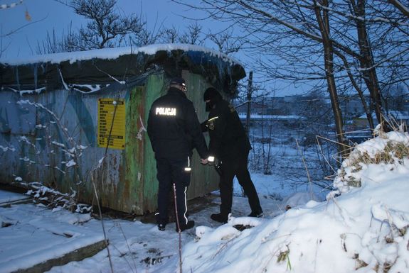 Policjant i strażnik miejski kontrolują opuszczony budynek